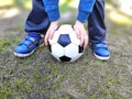 Boys legs and ball holding hands on green grass. Royalty Free Stock Photo